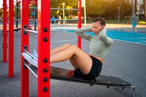 Sit-ups exercises. Active, fit sporty woman doing situps, exercising and training for fitness outdoor gym photo