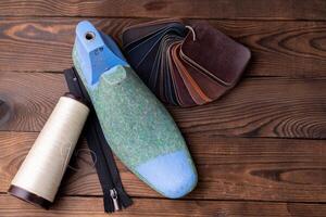 Leather samples for shoes and wooden shoe last on dark wooden table. photo