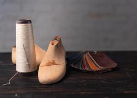 Leather samples for shoes and wooden shoe last on dark wooden table. photo