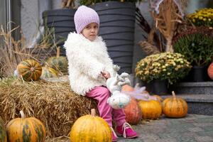 Unhappy little girl sitting outdoor near Halloween pumpkin autumn season Caucasian female child losy in city sitting sad photo