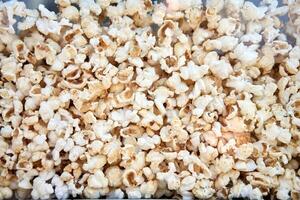 Popcorn background behind glass in a po pcorn maker. photo