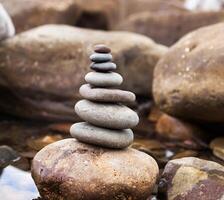 pirámide de piedras en un antecedentes mar de grande piedras y agua foto