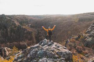 Traveller in a yellow jacket standing on the edge of a rock enjoying a moment of relaxation and a view of the Divoke sarky valley, Prague, Czech Republic. Achieving success photo