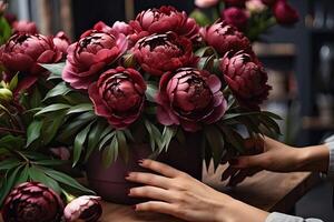 AI generated A female florist collects a bouquet of pions- fresh cut flowers in boxes and vases in a warehouse and racks for sale, delivery for the holiday. Spring, March 8, women's Day, birthday. photo