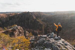 Traveller in a yellow jacket standing on the edge of a rock enjoying a moment of relaxation and a view of the Divoke sarky valley, Prague, Czech Republic. Achieving success photo