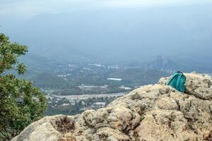 Serene Mountain Summit View with Teal Backpack Resting on Rocky Outcropping. Kemer, Turkey photo