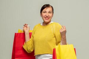 retrato de un contento adulto mujer con regalo pantalones en un gris fondo.comprador. foto