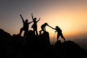 silueta de grupo equipo turistas presta Ayudar mano escalada acantilados montañas Ayudar mano. trabajo en equipo personas escaladores escalada parte superior superar dificultades, trabajo en equipo Ayudar mano negocio viaje concepto. foto