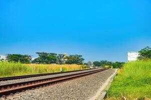 double track railway track that curves across the north of the island of Java with a bright blue sky photo