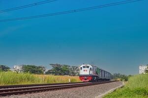 a series of cargo trains with green carriages pulled by a CC201 locomotive made by General Electric belonging to the Indonesian Railway Company, Indonesia, 28 October 2023. photo