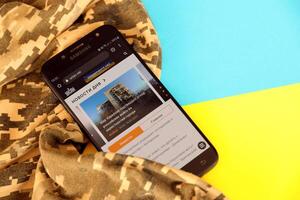 KYIV, UKRAINE - 4 MAY, 2023 Unian ukrainian news portal on smartphone screen with ukrainian flag and camouflage fabric photo