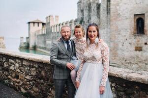 A happy young family walks through the old town of Sirmione in Italy.Stylish family in Italy on a walk photo