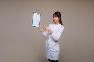 Portrait of a female medical worker in a gray background with a medical report.Girl doctor with a Notepad photo