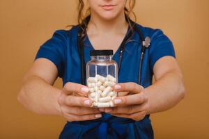 white pills in a jar of a female doctor. The doctor shows the vitamin capsules.Medicinal capsules. photo