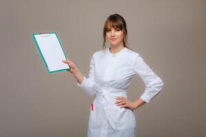 Portrait of a female medical worker in a gray background with a medical report.Girl doctor with a Notepad photo