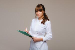 retrato de un hembra médico trabajador en un gris antecedentes con un médico informe.chica médico con un bloc foto