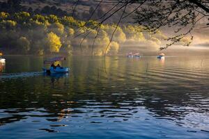 Paddleboats or pedal boats on the lake at sunset with haze or mist photo