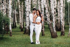 un joven hermosa Pareja en blanco ropa en contra el antecedentes de un abedul arboleda.retrato de personas en amor en un parque en naturaleza. foto