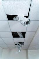 Empty industrial facility with grey wall. Internet cable hangs from the ceiling. Air conditioning tube. Closeup photo