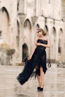 A stylish bride in a black wedding dress poses in the ancient French city of Avignon. Model in a beautiful black dress. Photo shoot in Provence.