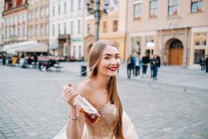 un novia en un Boda vestir con largo pelo y un bebida botella en el antiguo pueblo de Breslavia. Boda foto disparar en el centrar de un antiguo polaco ciudad.wroclaw, Polonia