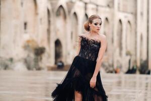 A stylish bride in a black wedding dress poses in the ancient French city of Avignon. Model in a beautiful black dress. Photo shoot in Provence.