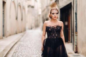 un elegante novia en un negro Boda vestir poses en el antiguo francés ciudad de Aviñón. modelo en un hermosa negro vestido. foto disparar en provenza