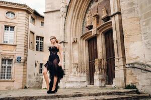 un elegante novia en un negro Boda vestir poses en el antiguo francés ciudad de Aviñón. modelo en un hermosa negro vestido. foto disparar en provenza