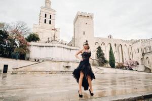 A stylish bride in a black wedding dress poses in the ancient French city of Avignon. Model in a beautiful black dress. Photo shoot in Provence.