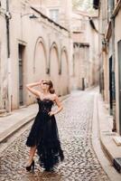 A stylish bride in a black wedding dress poses in the ancient French city of Avignon. Model in a beautiful black dress. Photo shoot in Provence.