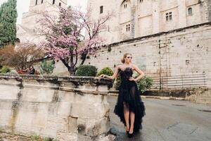 A stylish bride in a black wedding dress poses in the ancient French city of Avignon. Model in a beautiful black dress. Photo shoot in Provence.