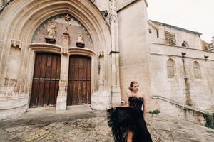 un elegante novia en un negro Boda vestir poses en el antiguo francés ciudad de Aviñón. modelo en un hermosa negro vestido. foto disparar en provenza