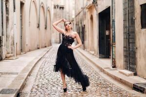 un elegante novia en un negro Boda vestir poses en el antiguo francés ciudad de Aviñón. modelo en un hermosa negro vestido. foto disparar en provenza