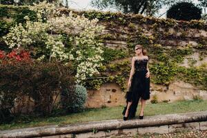 A stylish bride in a black wedding dress poses in the ancient French city of Avignon. Model in a beautiful black dress. Photo shoot in Provence.