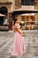 un joven hermosa novia soportes a el centrar de el antiguo ciudad de florencia en Italia. novia en un hermosa rosado vestir con un ramo de flores en toscana.italia foto