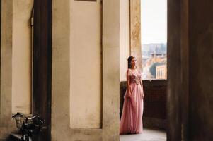 un joven hermosa novia soportes a el centrar de el antiguo ciudad de florencia en Italia. novia en un hermosa rosado vestir en toscana.italia foto