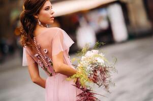 un joven hermosa novia soportes a el centrar de el antiguo ciudad de florencia en Italia. novia en un hermosa rosado vestir con un ramo de flores en toscana.italia foto