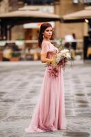 un joven hermosa novia soportes a el centrar de el antiguo ciudad de florencia en Italia. novia en un hermosa rosado vestir con un ramo de flores en toscana.italia foto