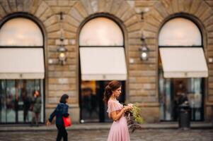 un joven hermosa novia soportes a el centrar de el antiguo ciudad de florencia en Italia. novia en un hermosa rosado vestir con un ramo de flores en toscana.italia foto