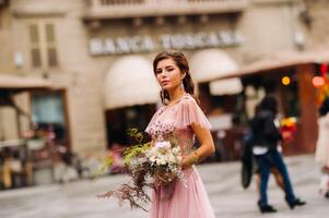 un joven hermosa novia soportes a el centrar de el antiguo ciudad de florencia en Italia. novia en un hermosa rosado vestir con un ramo de flores en toscana.italia foto