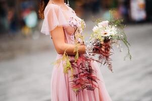 un joven hermosa novia soportes a el centrar de el antiguo ciudad de florencia en Italia. novia en un hermosa rosado vestir con un ramo de flores en toscana.italia foto