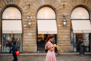 un joven hermosa novia soportes a el centrar de el antiguo ciudad de florencia en Italia. novia en un hermosa rosado vestir con un ramo de flores en toscana.italia foto