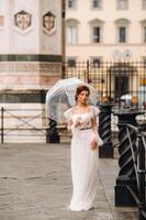 A beautiful stylish bride with an umbrella walks through the old city of Florence.Model with umbrellas in Italy.Tuscany. photo