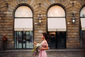 un joven hermosa novia soportes a el centrar de el antiguo ciudad de florencia en Italia. novia en un hermosa rosado vestir con un ramo de flores en toscana.italia foto