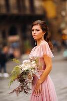 un joven hermosa novia soportes a el centrar de el antiguo ciudad de florencia en Italia. novia en un hermosa rosado vestir con un ramo de flores en toscana.italia foto