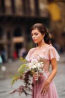 un joven hermosa novia soportes a el centrar de el antiguo ciudad de florencia en Italia. novia en un hermosa rosado vestir con un ramo de flores en toscana.italia foto