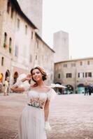 un novia en un blanco vestir en el antiguo pueblo de san gimignano.a niña camina alrededor el ciudad en italia.toscana. foto