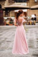 A young beautiful bride stands at the center of the Old city of Florence in Italy. Bride in a beautiful pink dress with a bouquet in Tuscany.Italy photo