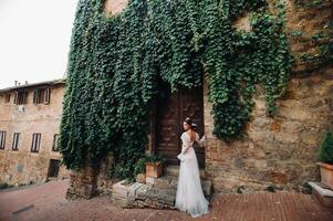 A bride in a white dress in the old town of San Gimignano.A girl walks around the city in Italy.Tuscany. photo