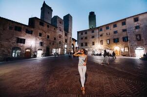 a girl in trousers and a t-shirt with glasses in the night city of San Gimignano.A girl walks around the city in Italy.Tuscany. photo